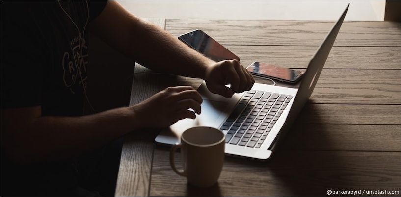 Mann sitzt vor Laptop mit einer Tasse