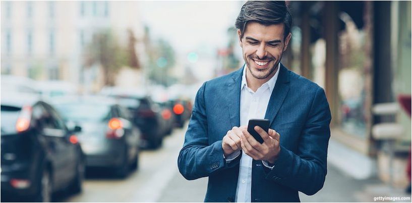 junger Geschäftsmann schaut auf das Telefon und lächelt