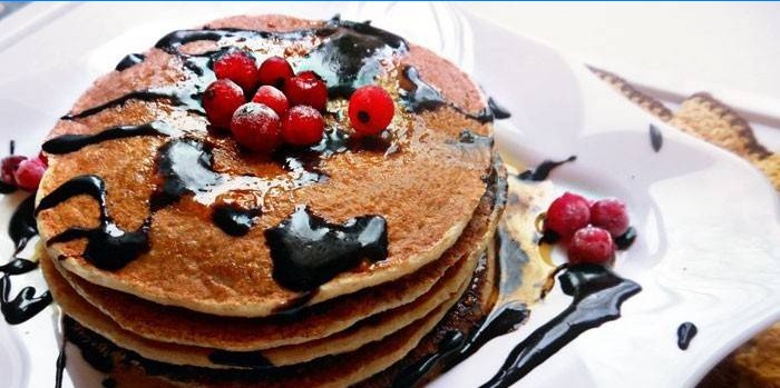 Fertige Pfannkuchen mit Schokoladensauce und Beeren auf einem Teller