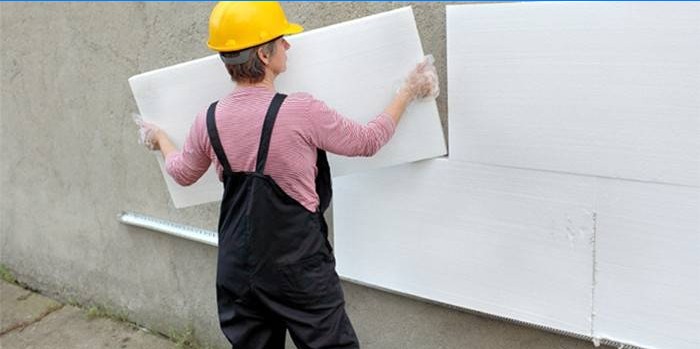 Ein Mann montiert Schaumstoffplatten an einer Fassadenwand