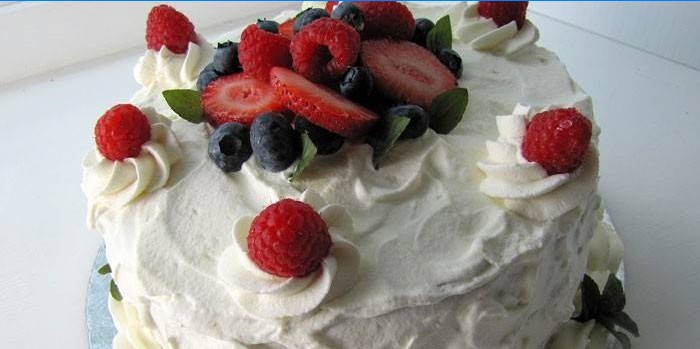 Kuchen mit Eiweißcreme und Beeren dekoriert.