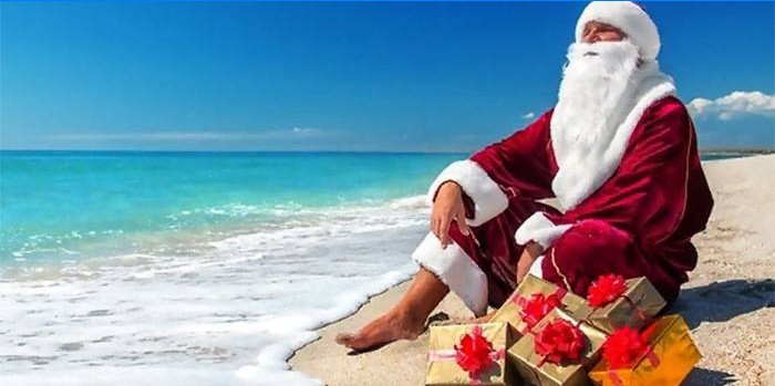 Weihnachtsmann mit Geschenken am Meeresstrand