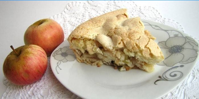 Ein Stück Apfelkuchen auf einem Teller und Äpfeln