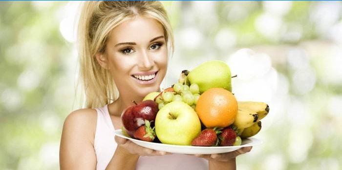 Mädchen hält ein Gericht mit Früchten und Beeren.