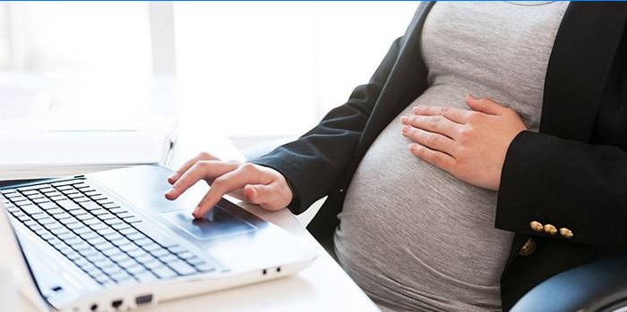 Schwangere Frau an einem Laptop