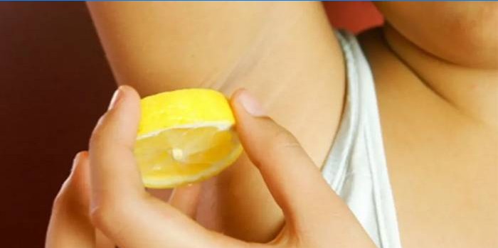 Frau reibt Achselhöhlen mit Zitrone