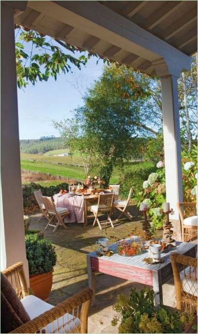 Holzmöbel und Korbstühle im Inneren der offenen Veranda